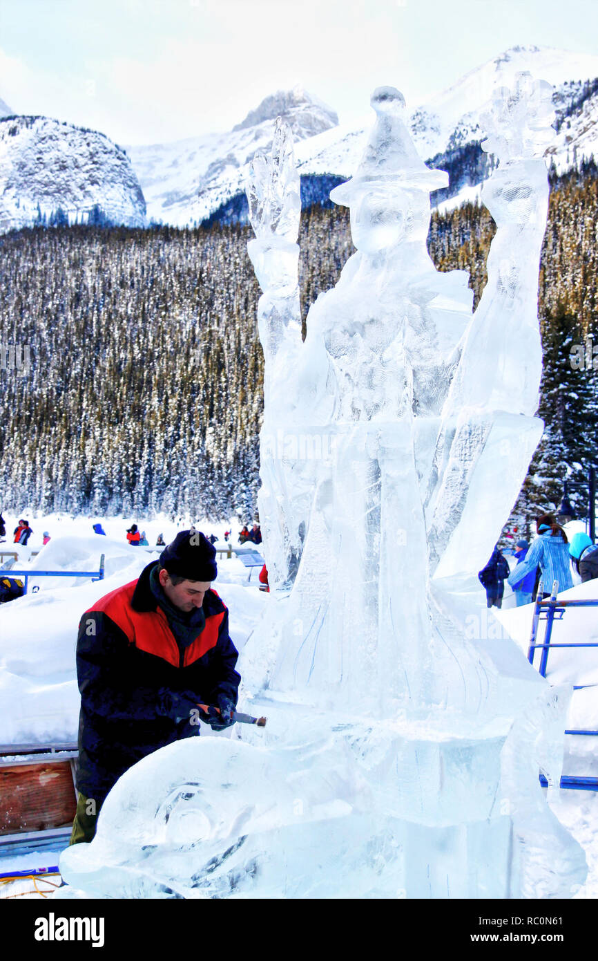 Il Lago Louise, CANADA - Jan 22, 2011: Un ghiaccio scultore scolpisce un alto blocco di ghiaccio con un utensile di potenza durante il ghiaccio annuale Magic Festival tenutosi in Cana Foto Stock