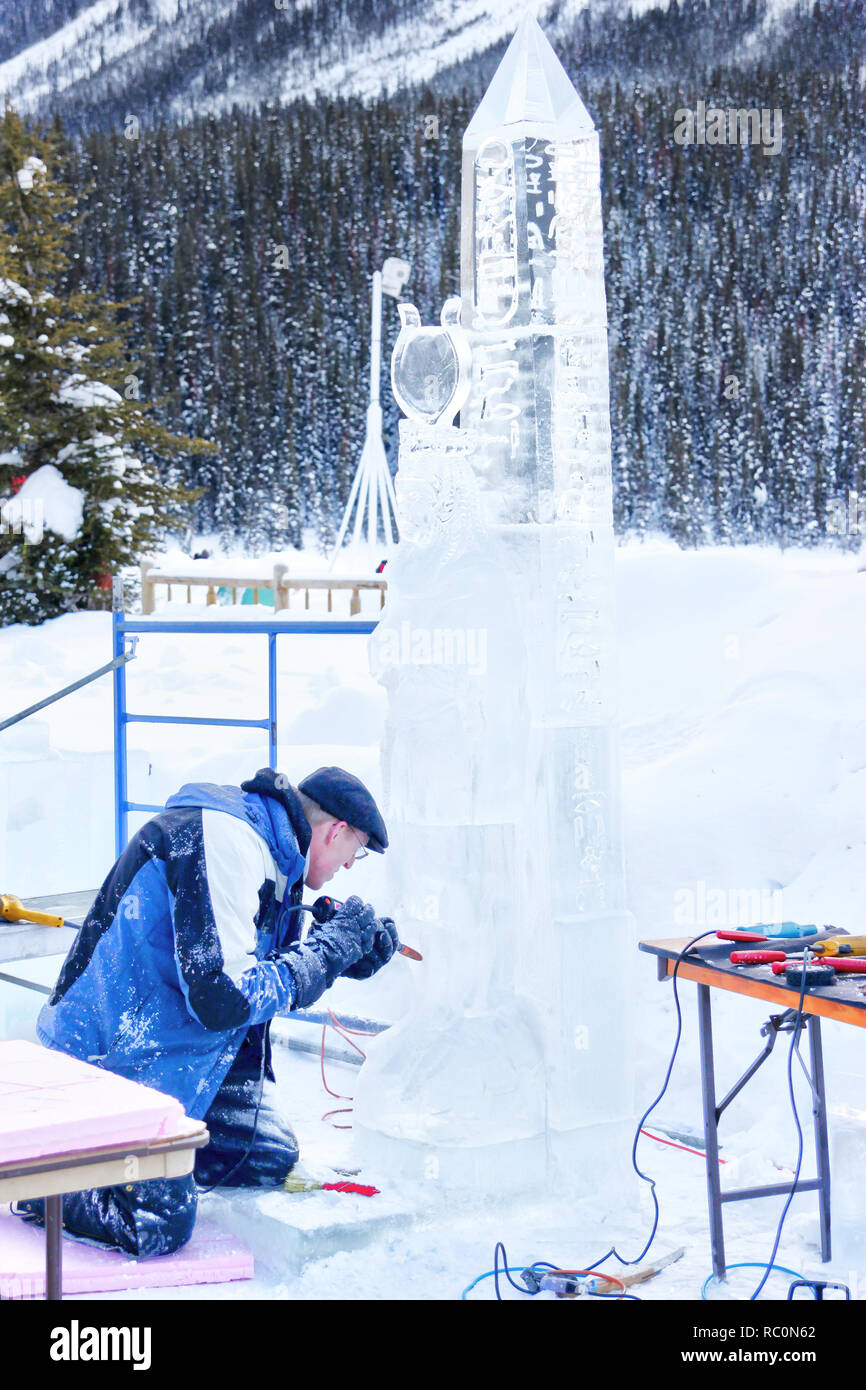 Il Lago Louise, CANADA - Jan 22, 2011: Un ghiaccio scultore scolpisce un alto blocco di ghiaccio con un utensile di potenza durante il ghiaccio annuale Magic Festival tenutosi in Cana Foto Stock