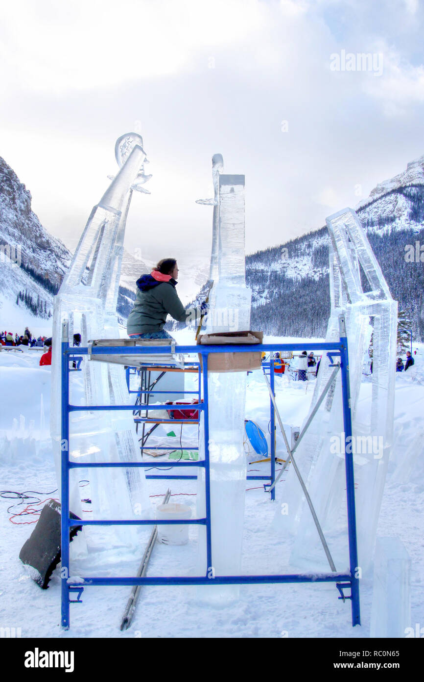 Il Lago Louise, CANADA - Jan 22, 2011: Un ghiaccio scultore scolpisce un alto blocco di ghiaccio con un intaglio strumento durante il ghiaccio annuale Magic Festival tenutosi a Ca Foto Stock