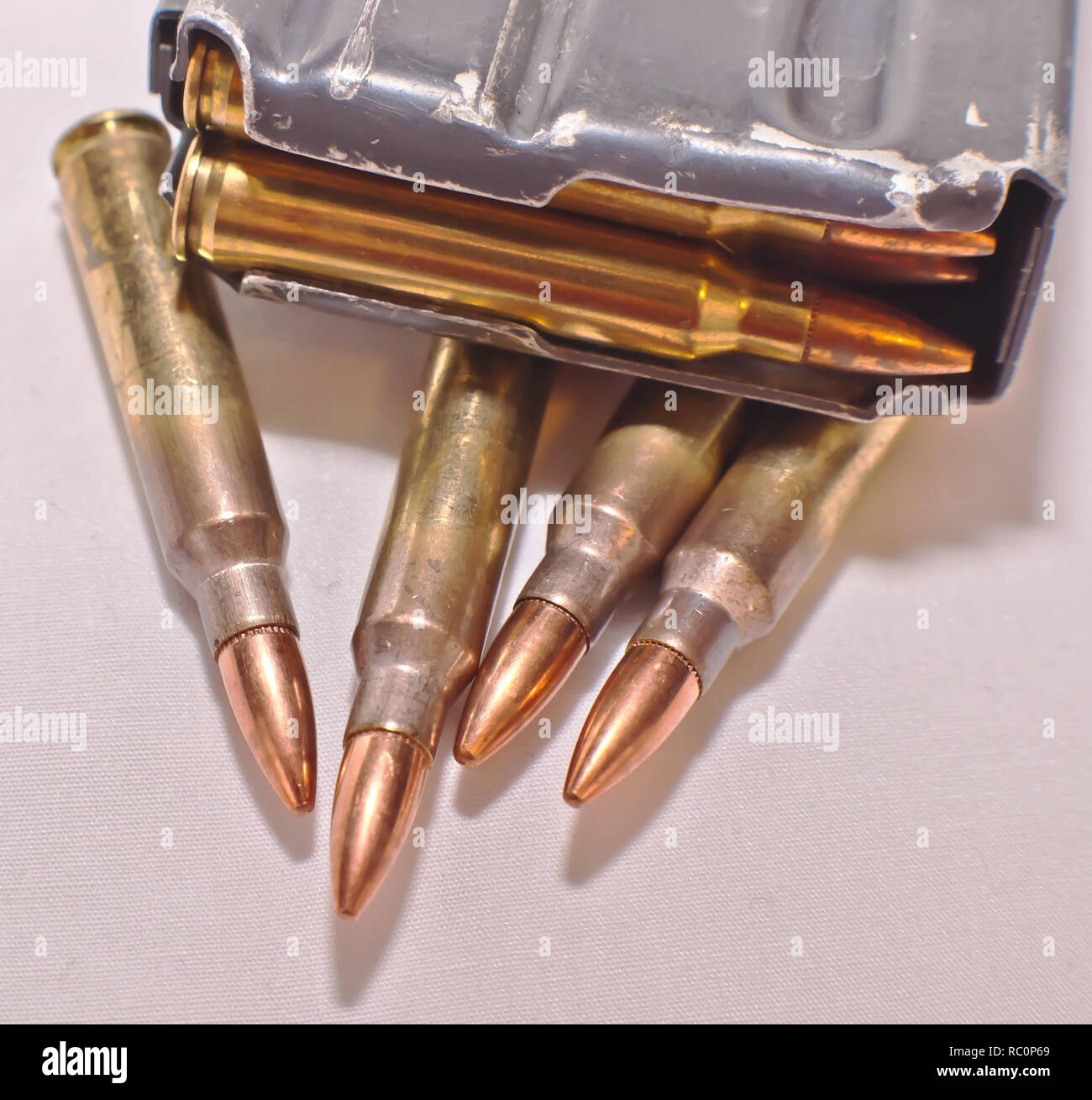 Un caricato AR-15 rifle magazine sulla parte superiore dei quattro .223 pallottole calibro su sfondo bianco Foto Stock