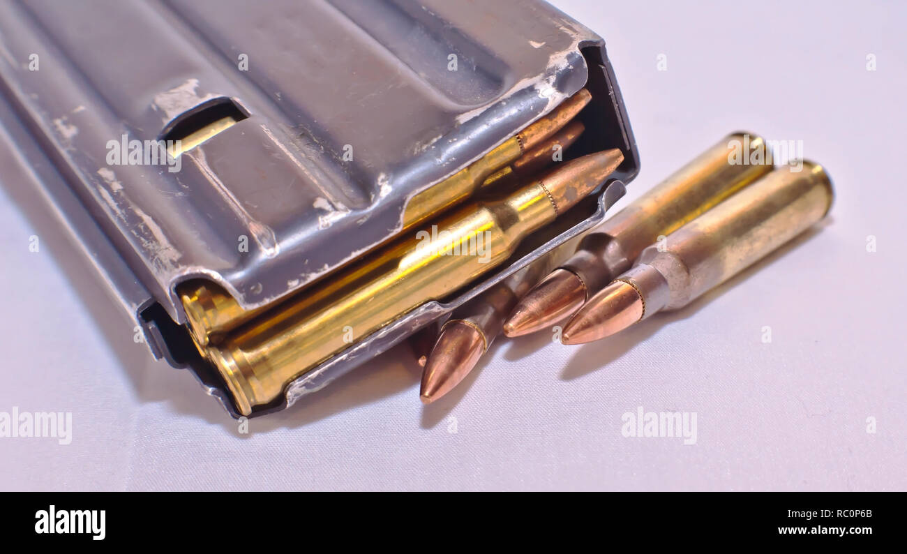 Un caricato AR-15 rifle magazine sulla parte superiore dei quattro .223 pallottole calibro su sfondo bianco Foto Stock