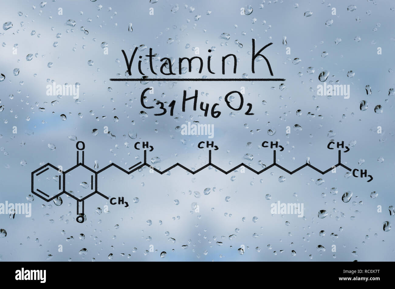 Il modello strutturale della vitamina K sul vetro con gocce di pioggia. Foto Stock