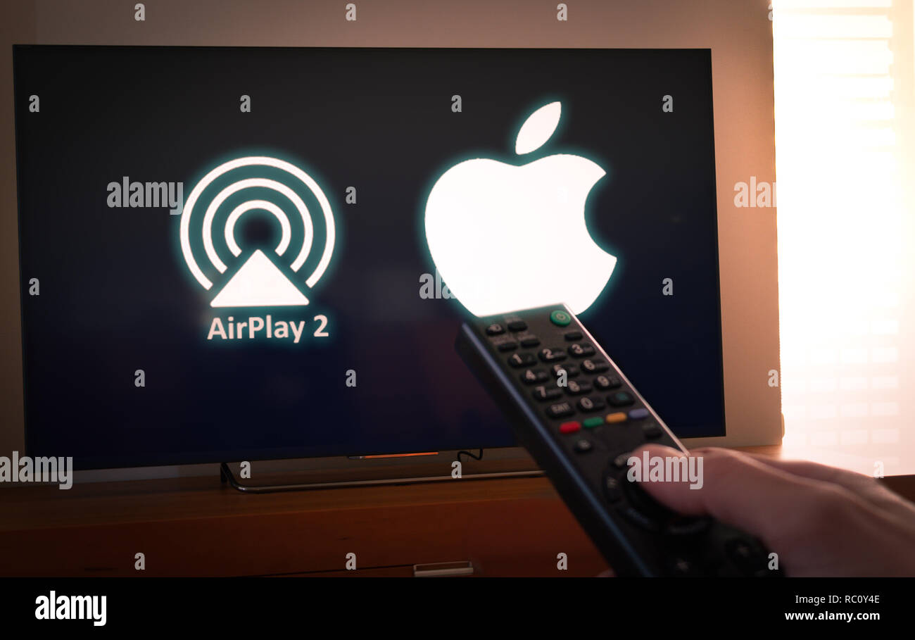 Barcellona, Spagna. Gennaio 2019: uomo detiene un telecomando con Apple e Airplay2 icona su schermo TV Foto Stock