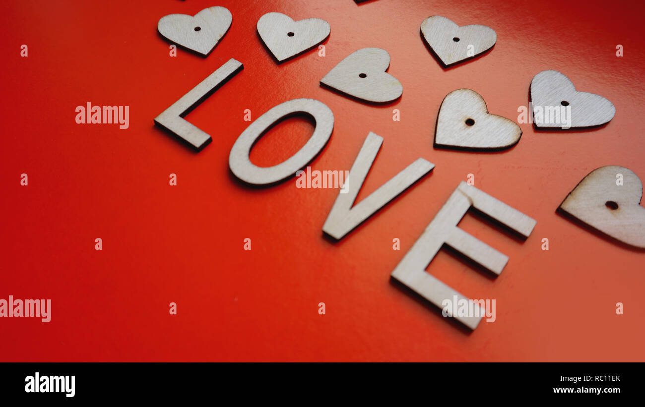 Il giorno di San Valentino sfondo rosso con cuori e lettere amore - fatta di legno su rosso Foto Stock
