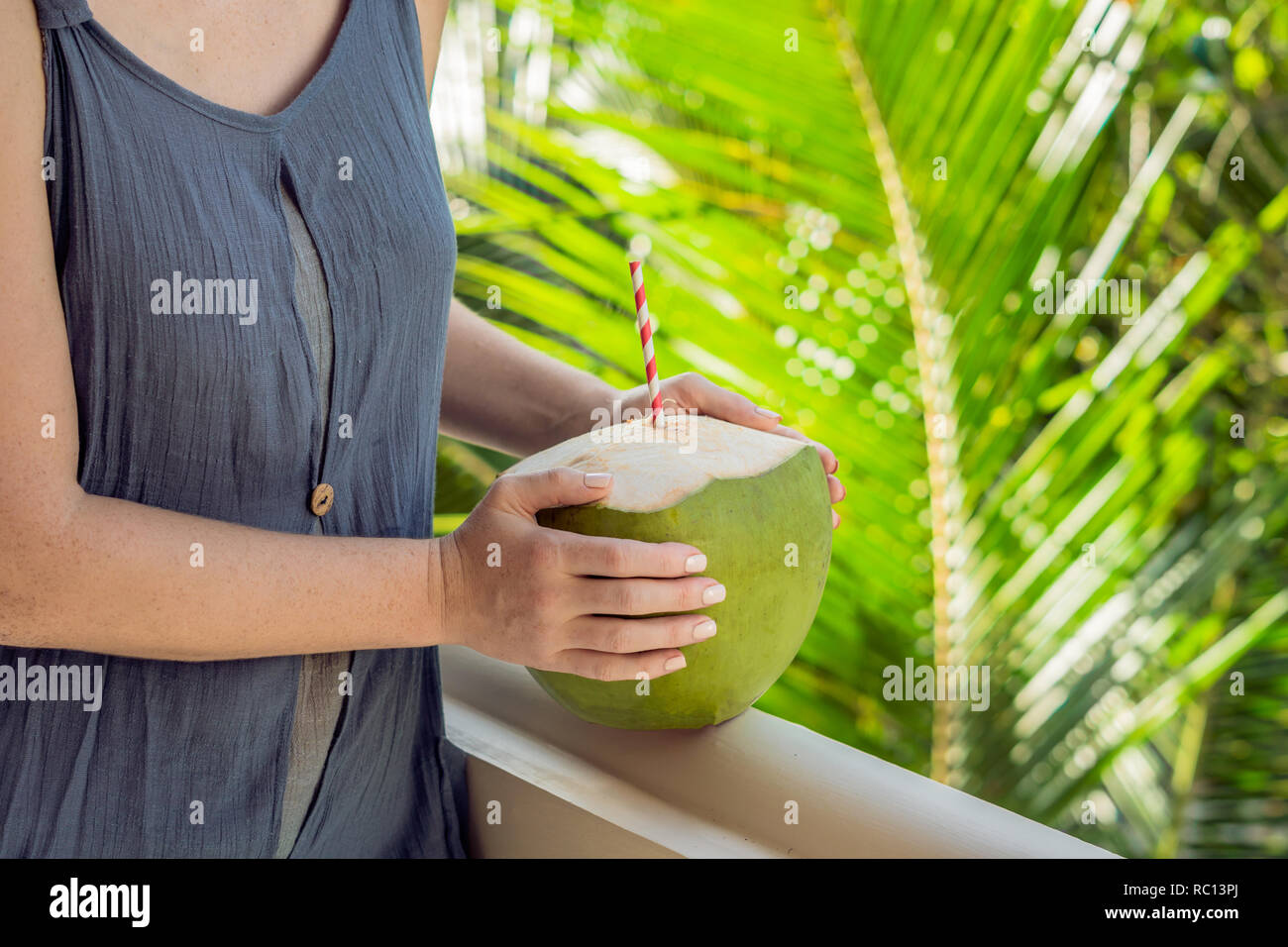 Noce di cocco in belle mani femminili su uno sfondo verde. I vantaggi di acqua di cocco Concept Foto Stock