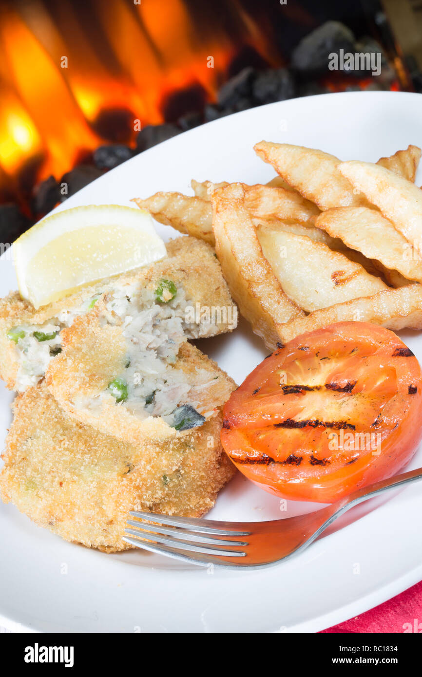 Placcato in un pranzo leggero in casa di sgombro e il segnale di PEA fishcakes con patatine/patatine fritte e grigliate di pomodoro e di limone fresco guarnire a cuneo. Foto Stock