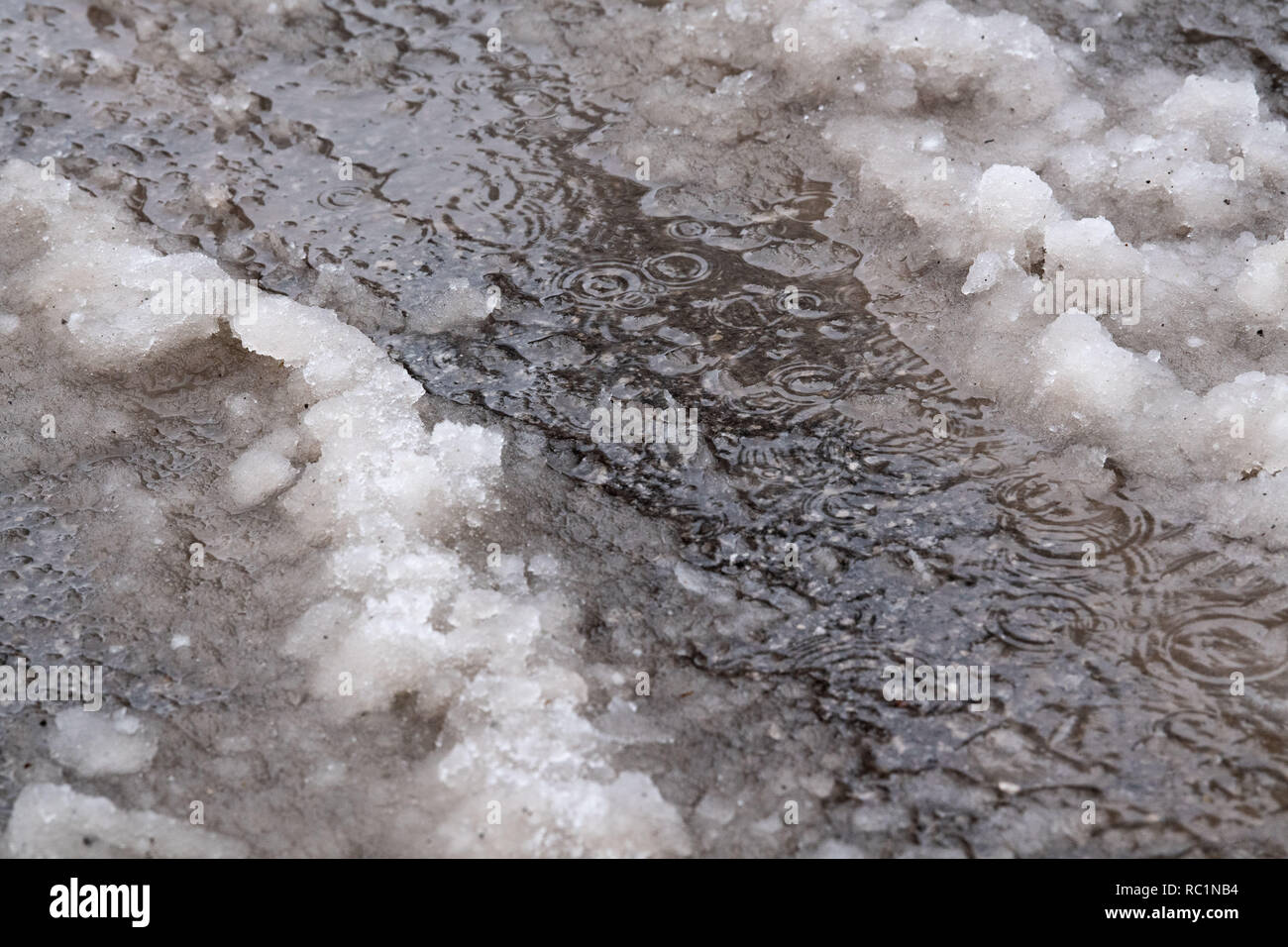 Rottach Egern, Germania. Xiii gen, 2019. Modulo di pozzanghere sulla strada accanto a granite. Dopo l intensa nevicata dei giorni scorsi, disgelo con la pioggia ha impostato in molti luoghi, aumentando il carico di neve sui tetti. Credito: Lino Mirgeler/dpa/Alamy Live News Foto Stock