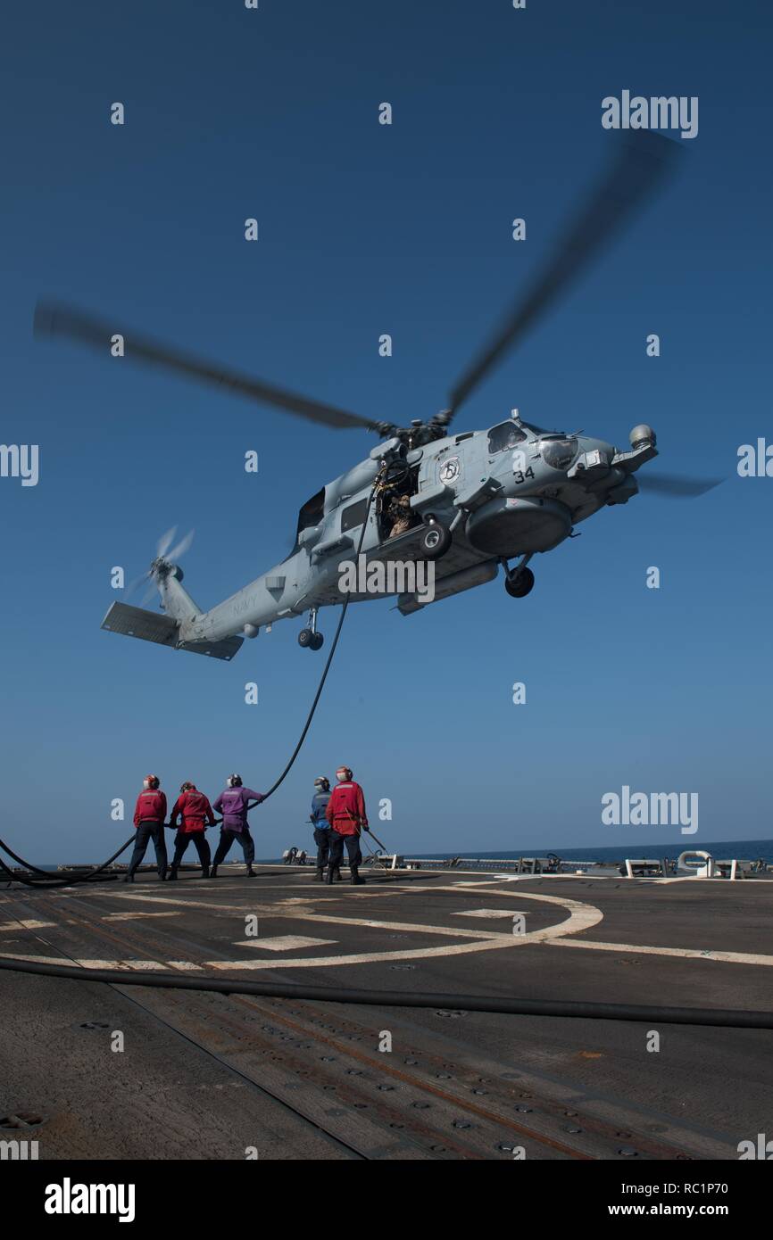 Stati Uniti I marinai di gestire un flessibile del carburante durante la conduzione di un elicottero della fornitura in volo con un MH-60R Sea Hawk, assegnato all'elicottero Maritime Strike Squadron (HSM) 37, sul ponte di volo dell'guidato-missile destroyer USS Chung-Hoon (DDG 93) nel Golfo di Aden, 8 gennaio, 2019. Il Chung-Hoon è distribuito negli Stati Uniti Quinta Flotta area di operazioni a sostegno di operazioni navali per garantire stabilità marittimo e la sicurezza nella regione centrale di collegamento del Mediterraneo e del Pacifico attraverso l'Oceano Indiano occidentale e tre strategici punti di strozzatura. (U.S. Foto di Marina di Massa lo specialista di comunicazione Foto Stock