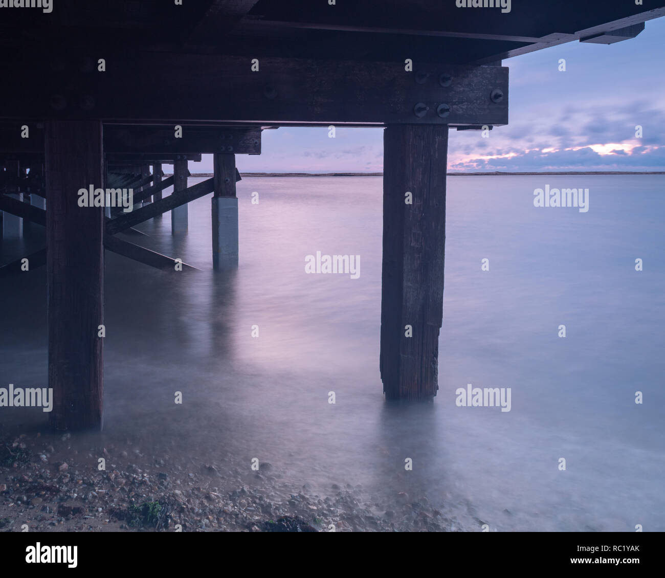 Una lunga esposizione al di sotto di un vecchio ponte di legno, ad alta marea in un freddo inverno mattina. Foto Stock