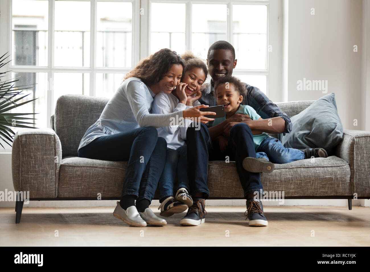 Felice famiglia africana con 2 bambini che si divertono con gadget Foto Stock