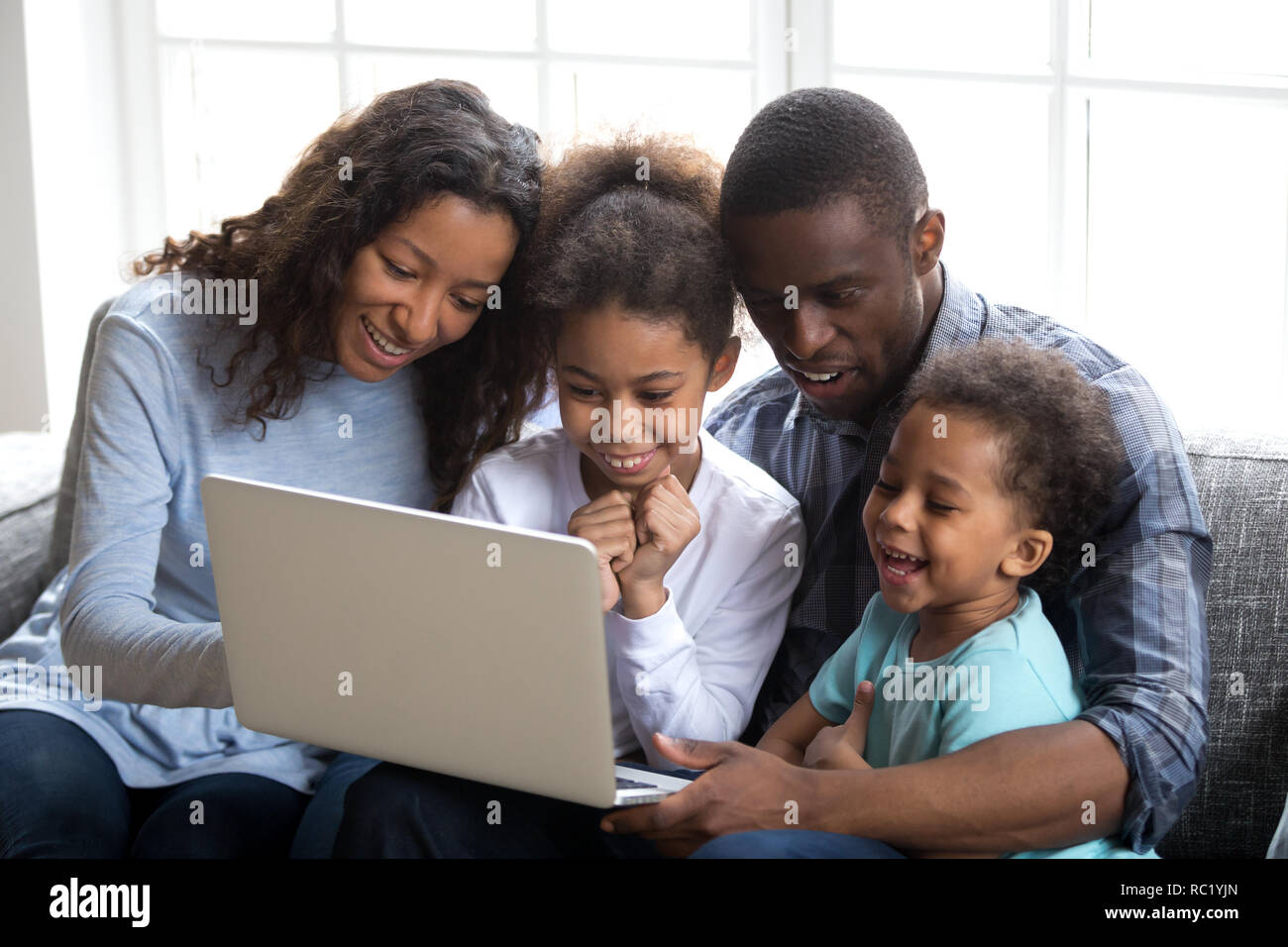 Felice famiglia africana con i bambini utilizzando laptop insieme a casa Foto Stock