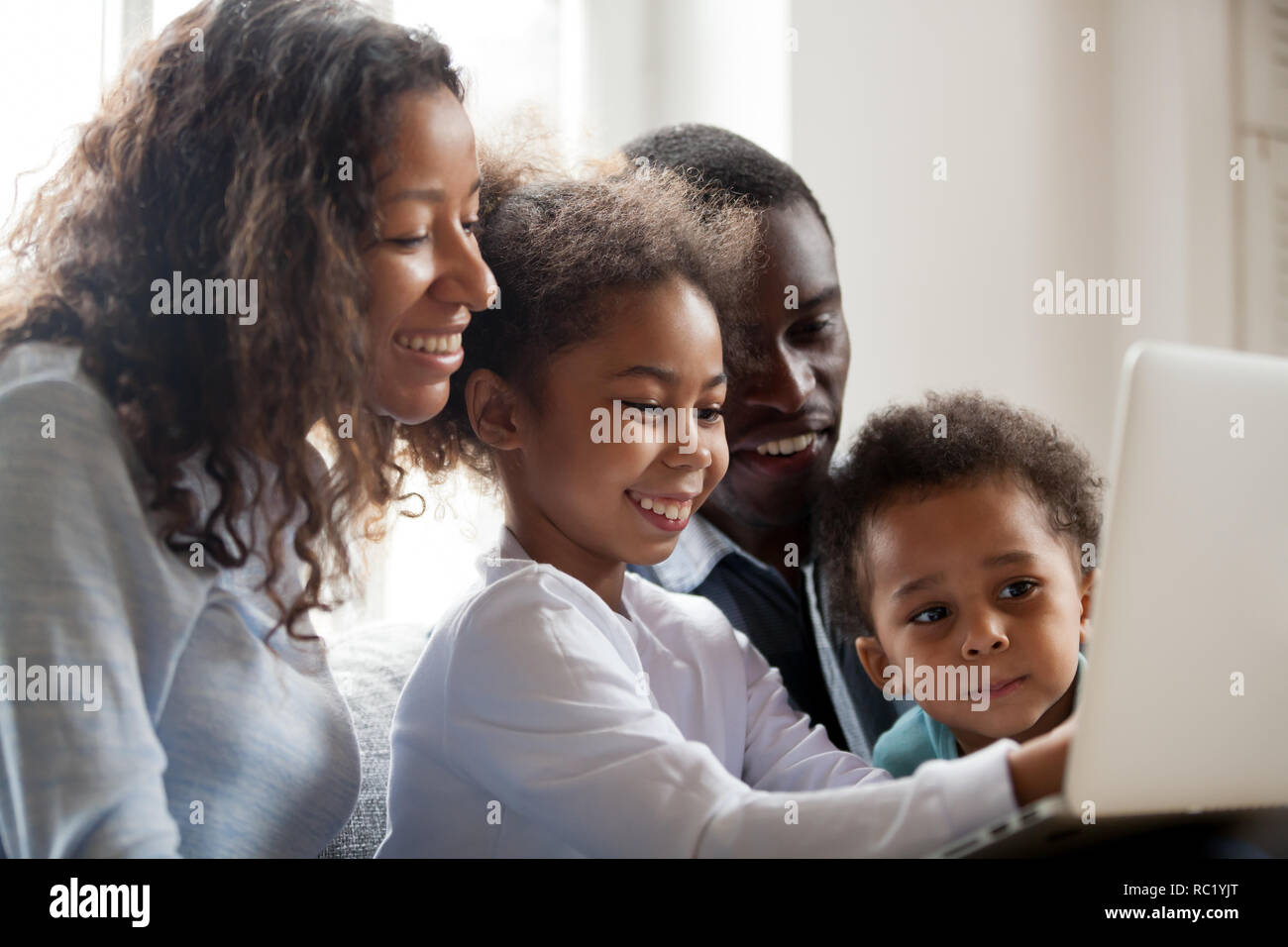 Africana di genitori e bambini di ridere facendo shopping online su l Foto Stock