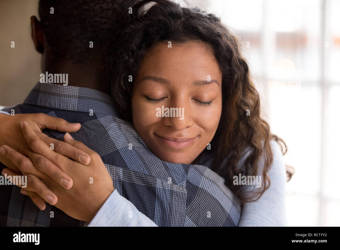 Felice African American moglie abbracciando il marito che tiene stretto feelin Foto Stock