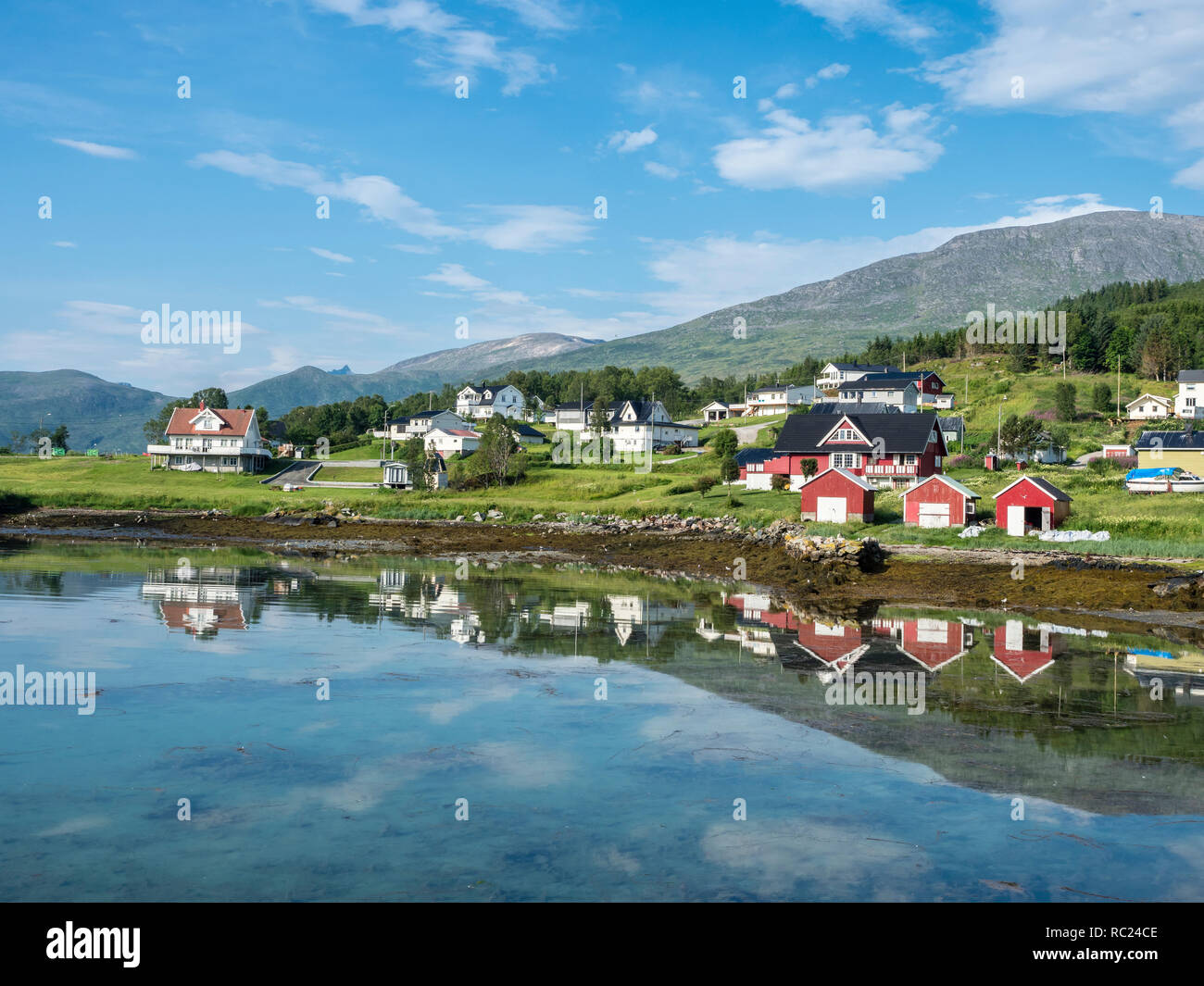 Botnham, presso il traghetto kai, barca capannoni e case, riflessioni sul mare calmo, Senja, Troms, Norvegia Foto Stock