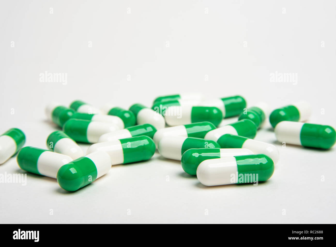 Medico generico pillole in verde e bianco abilmente sparsi su un bianco di carta senza giunture sfondo di un'immagine orizzontale formato. Foto Stock