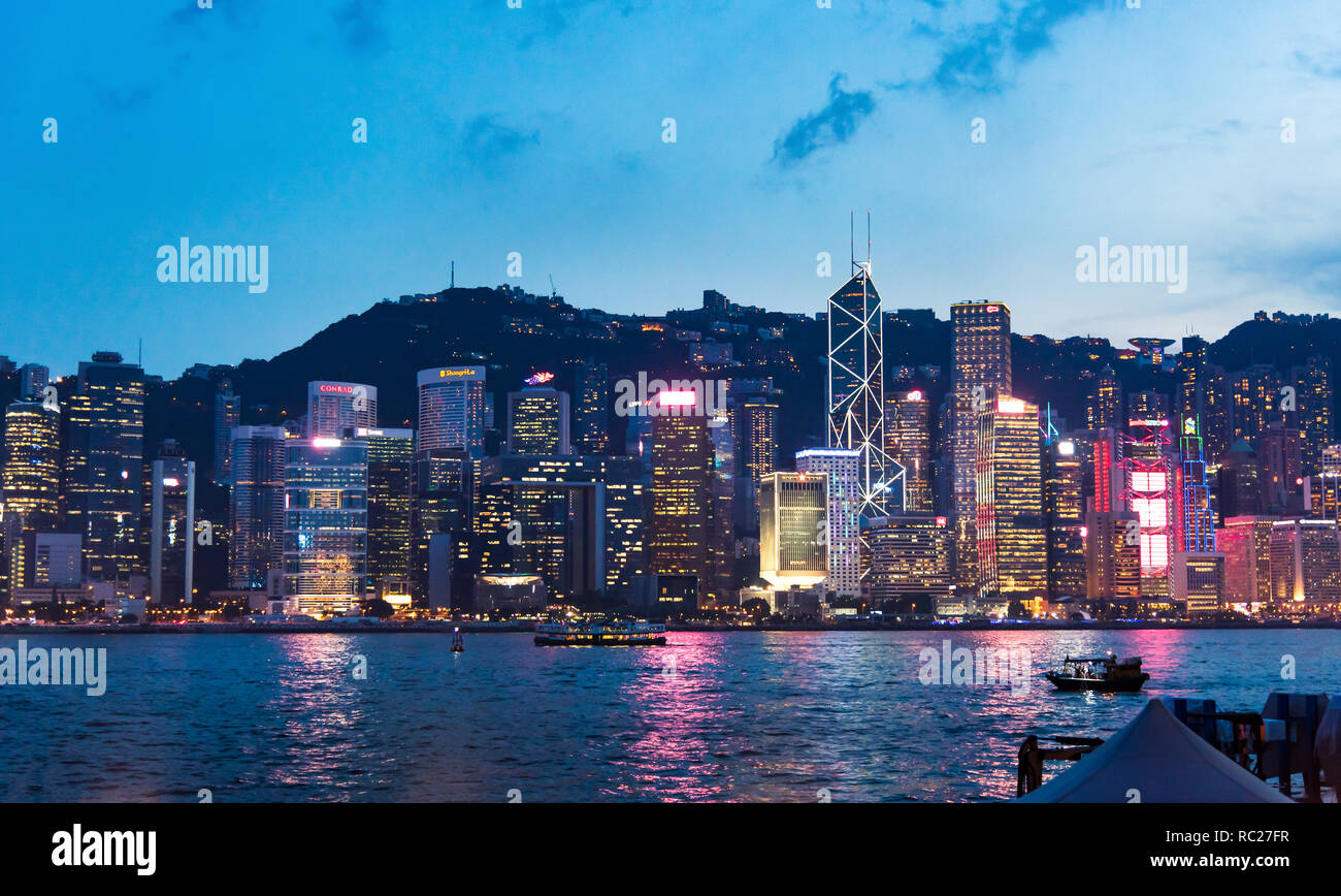 Hong Kong - Agosto 7, 2018: Hong Kong cityscape vista di moderni edifici del centro per l'acqua da Victoria Harbour a blue ora Foto Stock