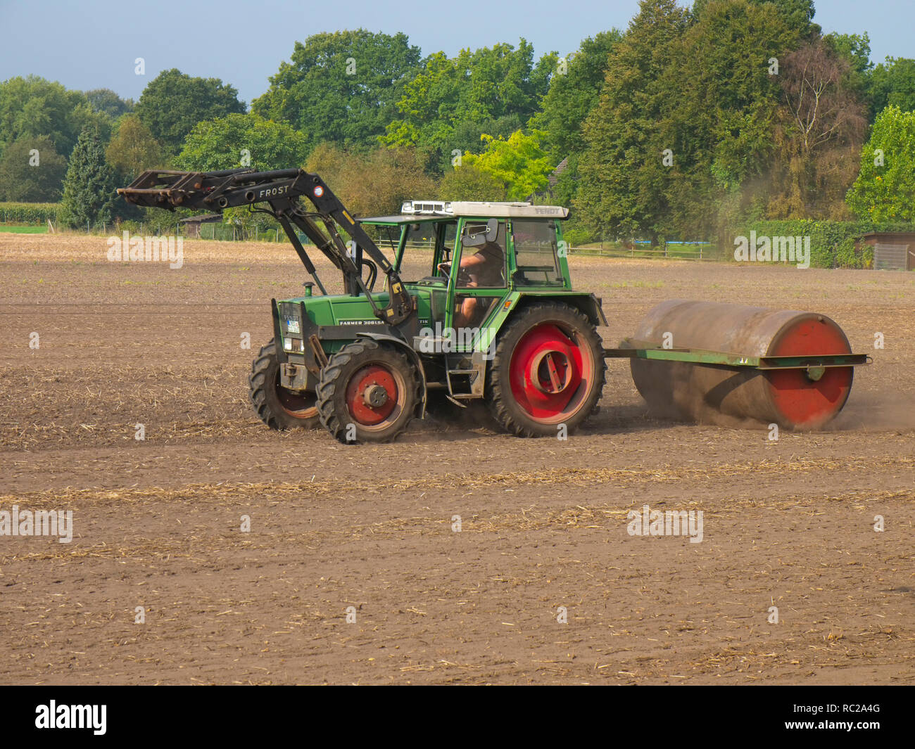 Agricoltore sul suo trattore appiattire un campo con la sua canna pesante vicino Mechtersen Germania del nord. Foto Stock