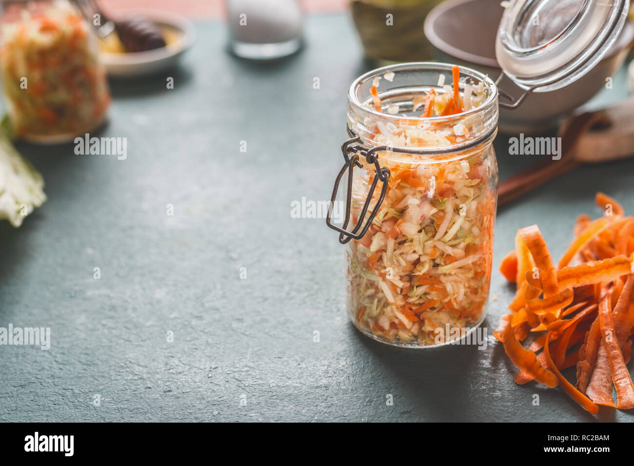 Semplice carota fresca insalata di cavolo in vasetti per salutare il pranzo è sul tavolo da cucina sfondo, vista frontale con copia spazio. Cibo vegetariano, a basso contenuto calorico Foto Stock