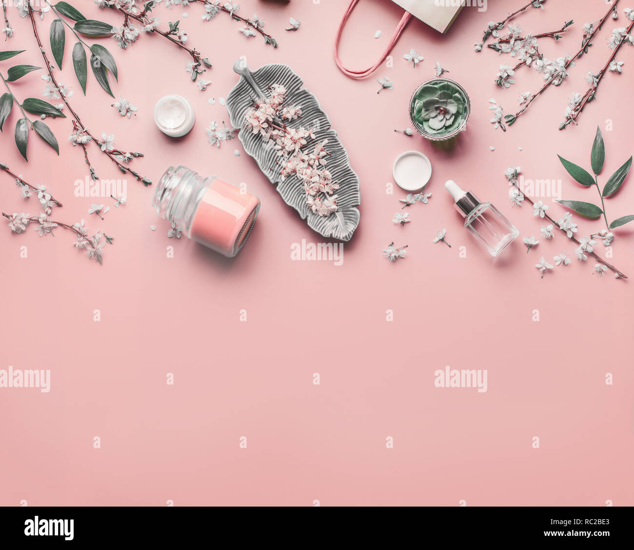 Cosmetici e per la cura della pelle del concetto. Varie Trattamento viso anti-invecchiamento prodotti sul rosa pastello con sfondo di fiori di ciliegio e foglie, vista dall'alto il telaio. Copia spa Foto Stock