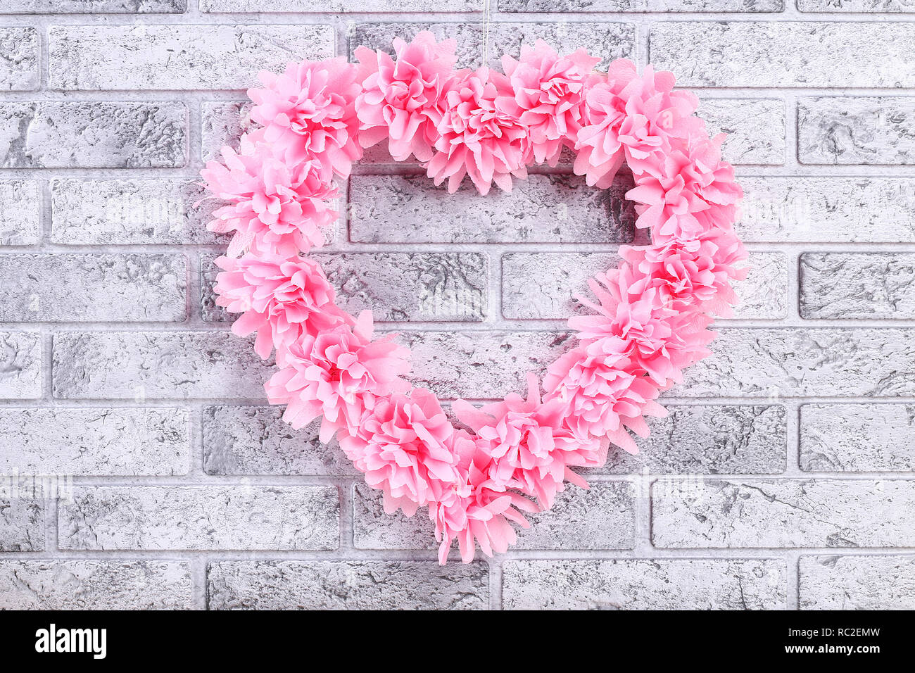 A forma di cuore decorata ghirlanda di fiori artificiali realizzati di  tessuto rosa di tovaglioli di carta. Idee regalo per il giorno di San  Valentino, arredamento per amore giorno, concetto Febbraio 14