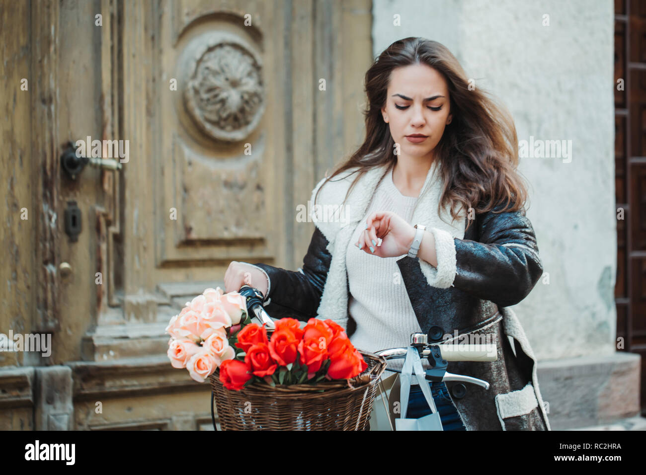 Bella giovane donna sorridente con la sua bicicletta guardando a guardare nella città. Foto Stock