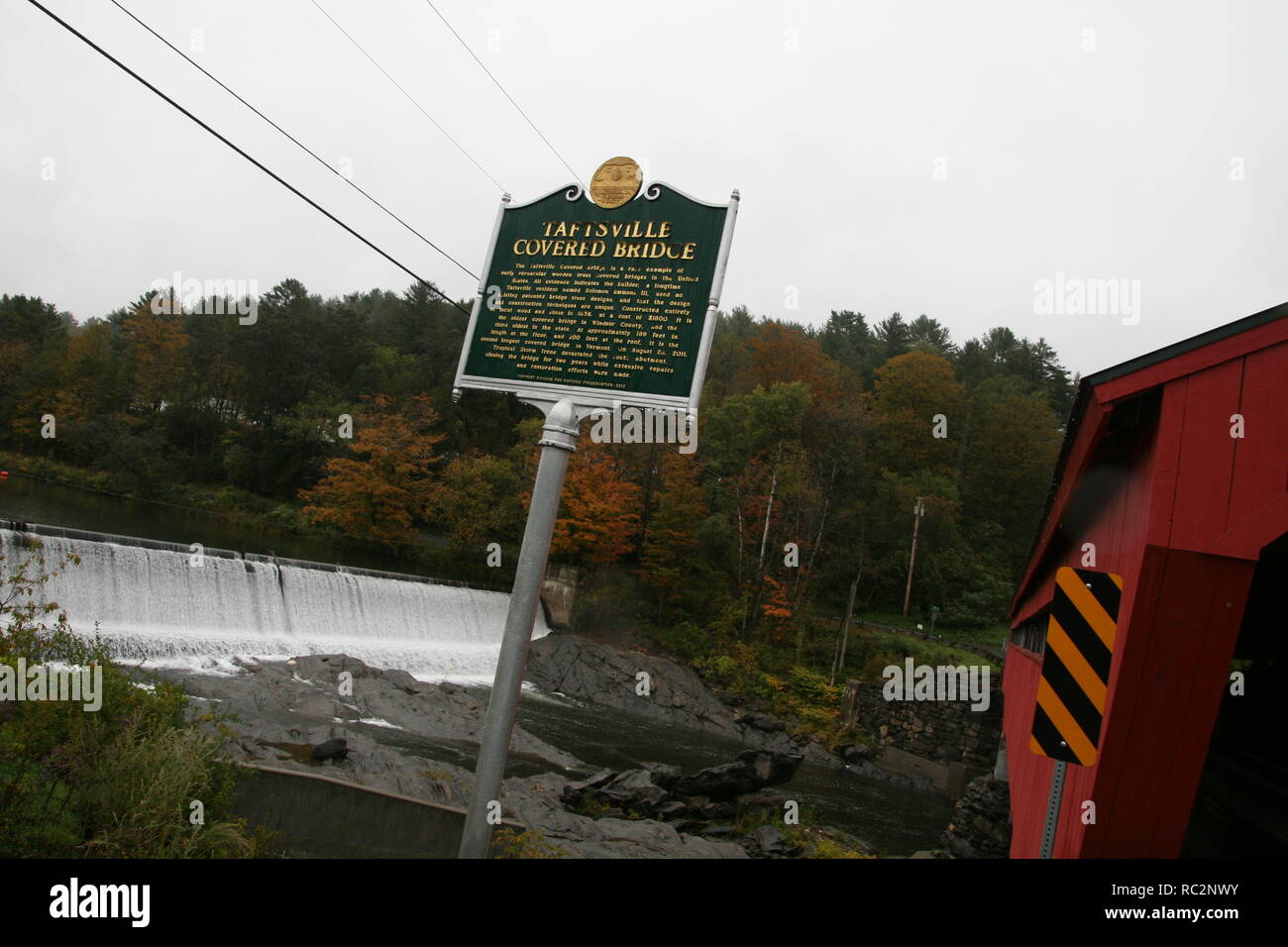 Vista di Taftsville ponte coperto, Vermont - focalizzazione sul segno del patrimonio che dettaglia storia dietro la sua costruzione e la vista al di là del fiume Ottauquechee Foto Stock