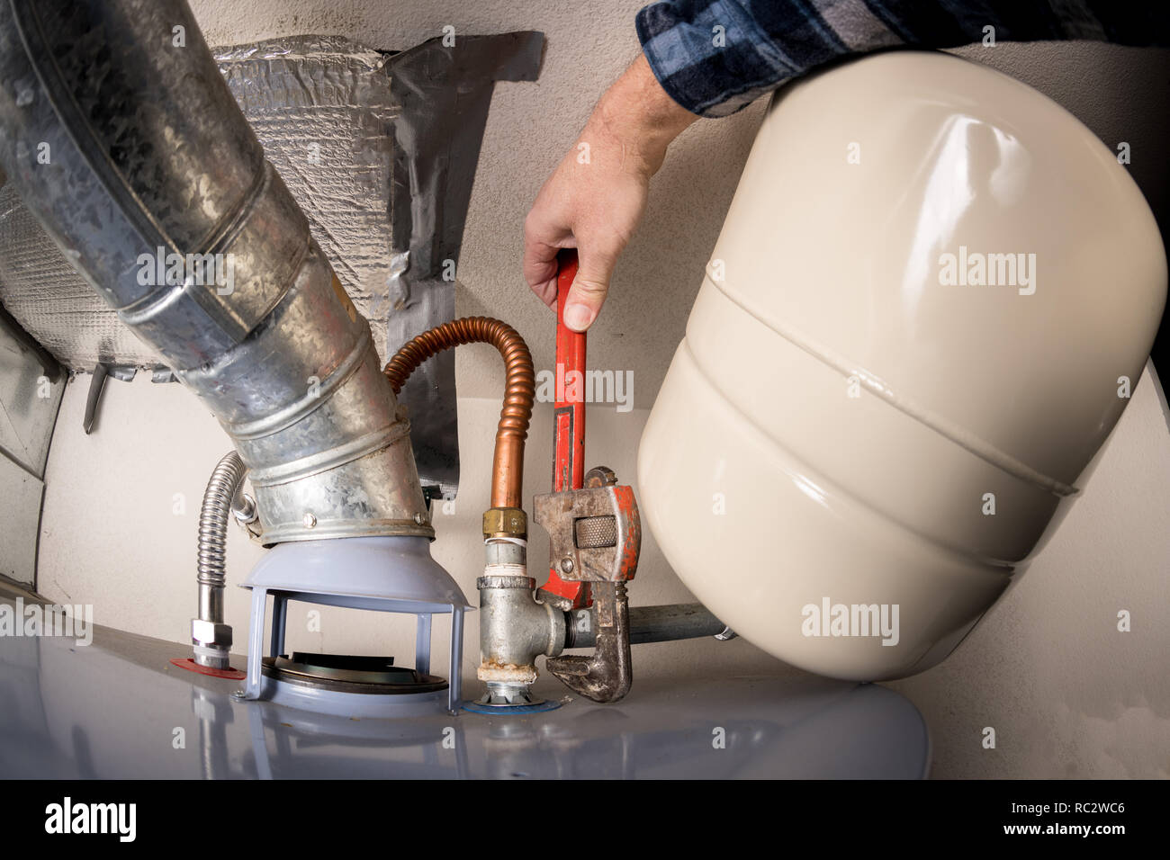 In prossimità della parte superiore di un riscaldatore di acqua calda con una chiave facendo il lavoro Foto Stock