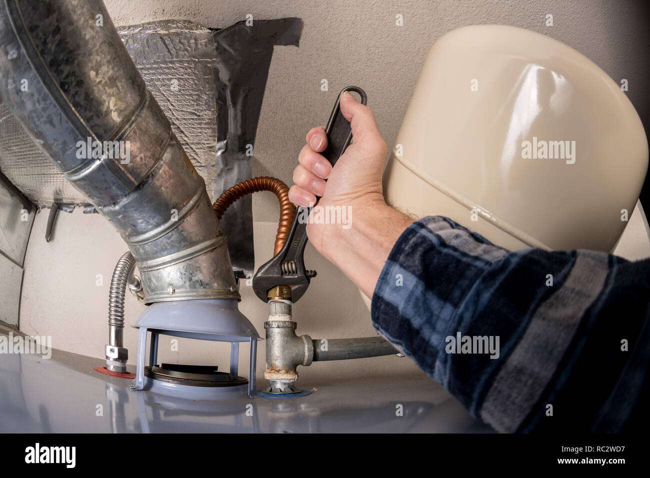 Chiave regolabile serrando un condotto su un riscaldatore di acqua da un idraulico Foto Stock