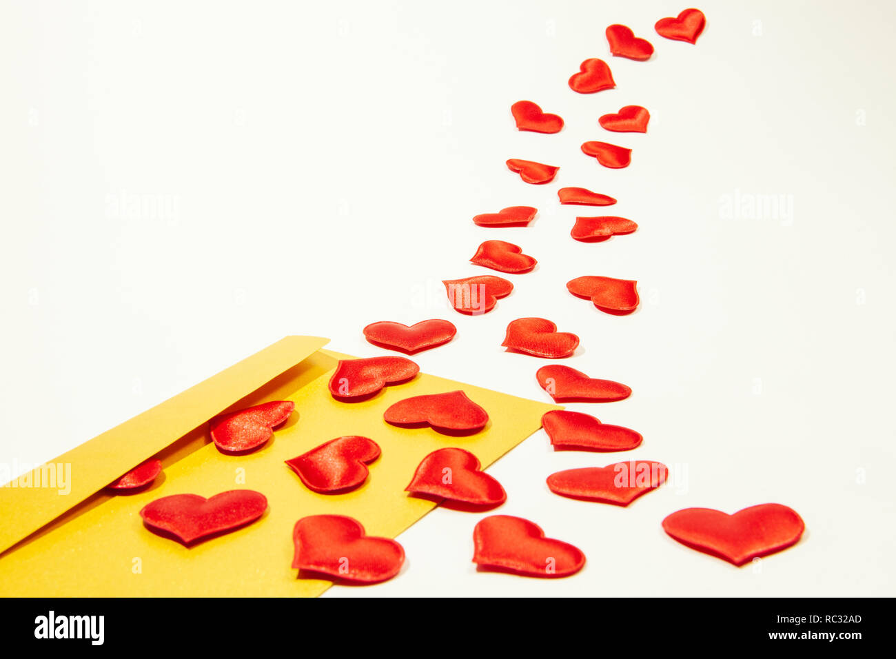 Lettera d'amore. Oro il giorno di San Valentino biglietto di auguri buste con il cuore. Cuori rossi si riversa fuori la busta sul bianco. Cuori volare fuori dalla busta. Foto Stock
