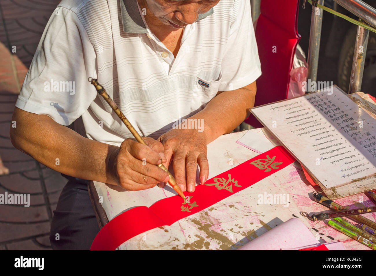 Un pittore dipinge calligraphed poesie per il nuovo anno cinese a Chinatown a Bangkok, in Thailandia Foto Stock