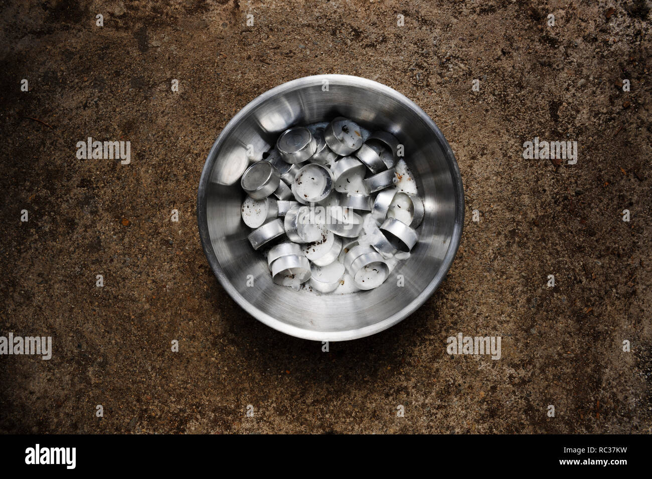 Ciotola di acciaio inossidabile pieno di parte bruciato di notte le luci (candele di cera) che sono fusi insieme come la cera raffreddata. Foto Stock