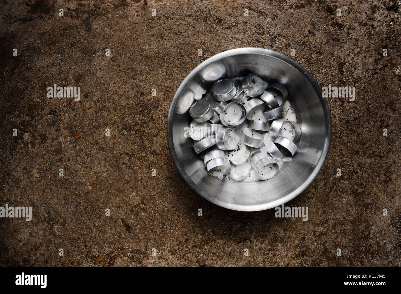 Ciotola di acciaio inossidabile pieno di parte bruciato di notte le luci (candele di cera) che sono fusi insieme come la cera raffreddata. Foto Stock