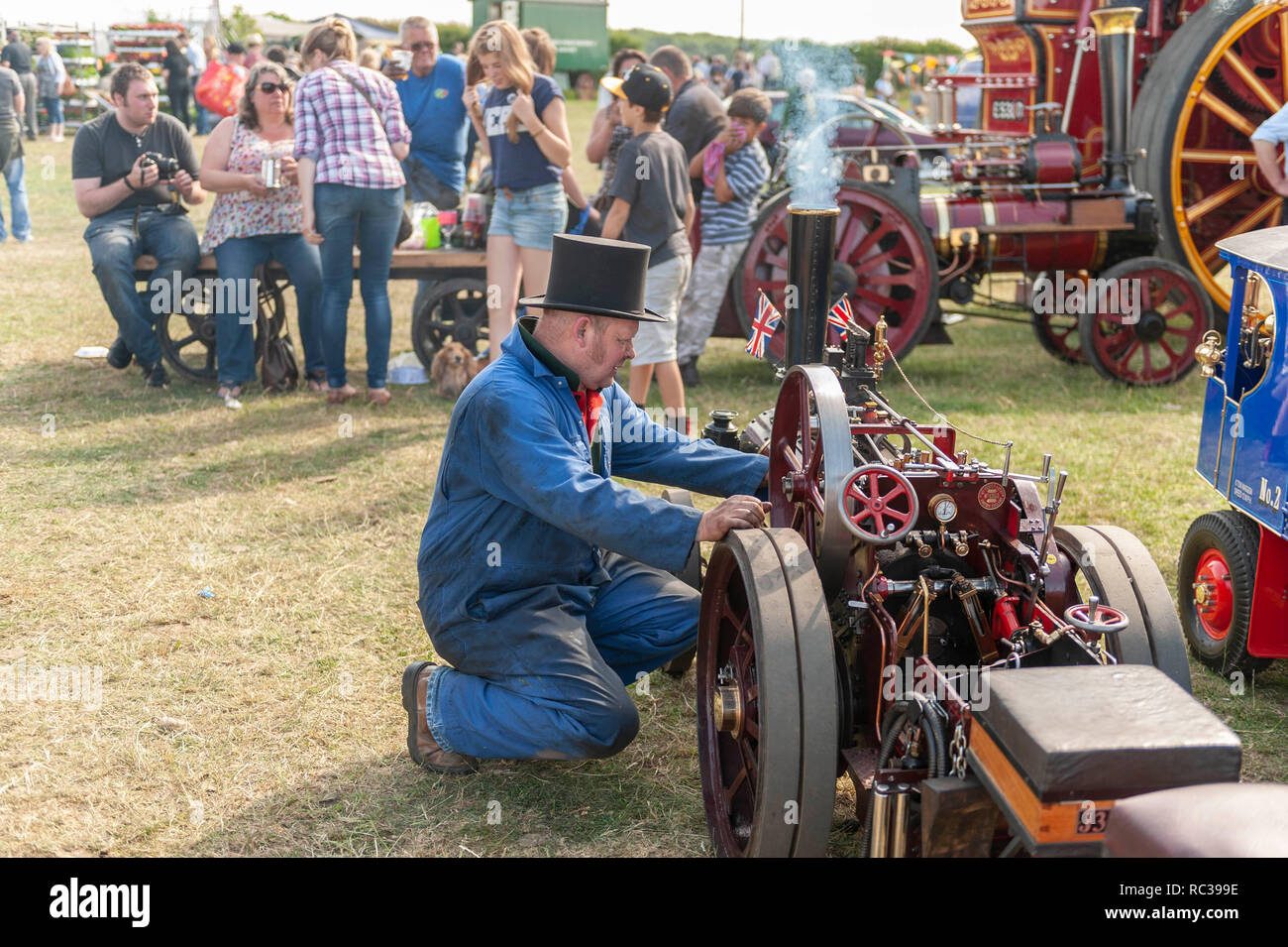 Uomo in ginocchio di fronte a una miniatura del motore di trazione a vapore di Preston Rally, Kent, Inghilterra Foto Stock