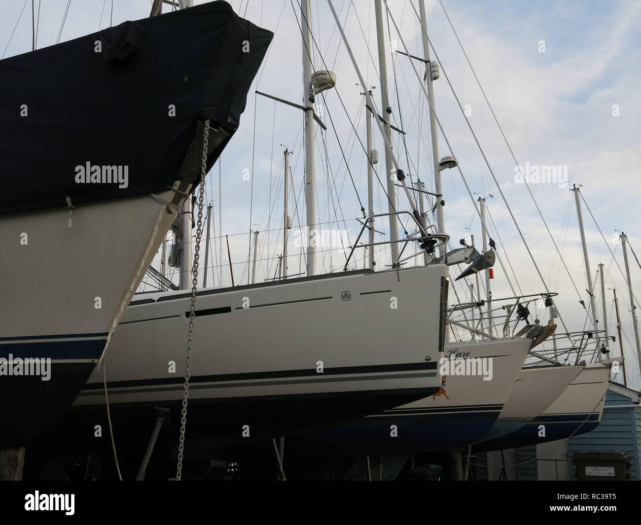 Close-up di cinque yacht ormeggiati in una fila allo Yacht Club sul fiume Deben a Waldringfield, Suffolk; Novembre 2018 Foto Stock