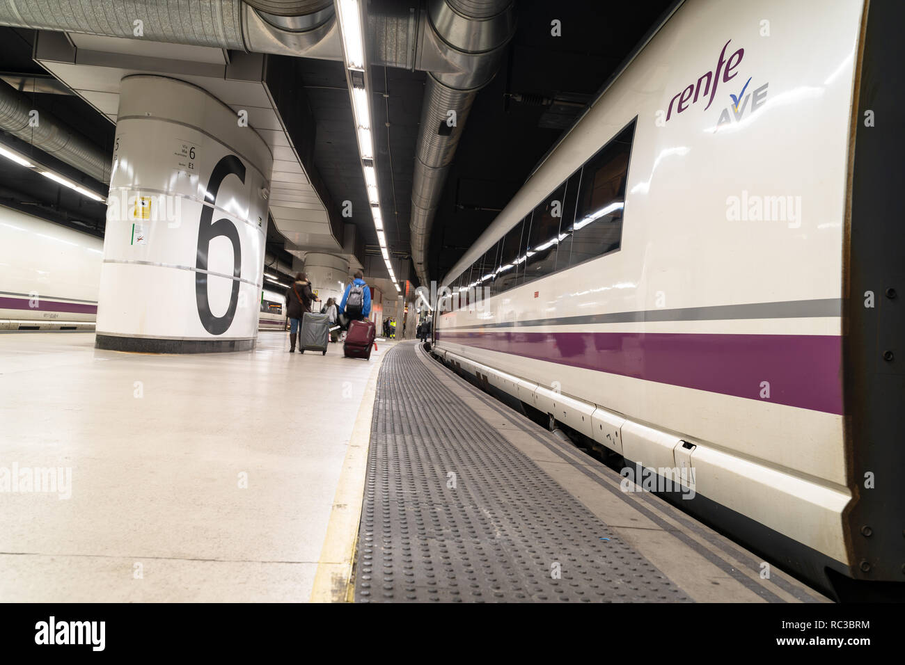 Treno ad alta velocità AVE parcheggiato sul binario numero 6 della stazione di Barcelona Sants e viaggiatori con le valigie lasciando alla stazione. Barcellona, ​Spain Foto Stock