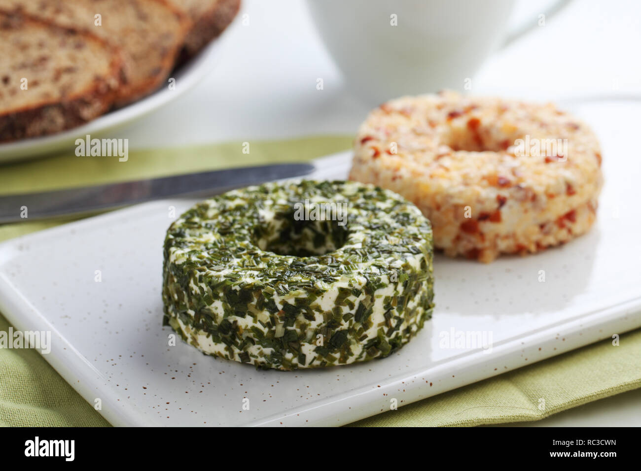 Turni di formaggi lettone con verdi, dadi e pepe su una ceramica tagliere Foto Stock