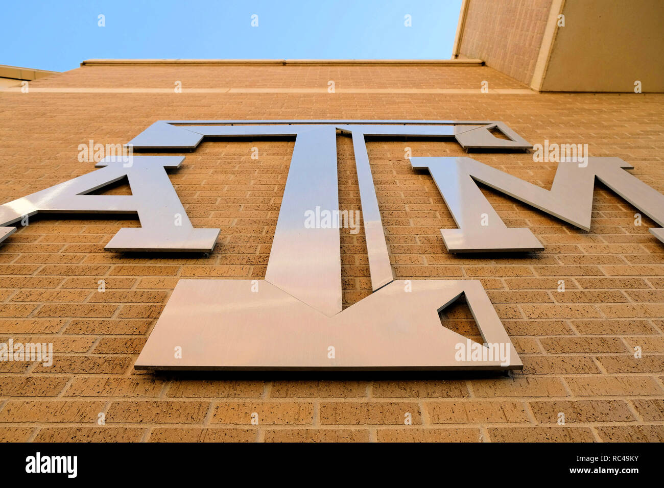 Texas A&M University del logo di metallo su un muro di mattoni guardando dal basso; presso il campus della Texas A&M University College Station, Texas, Stati Uniti d'America. Foto Stock