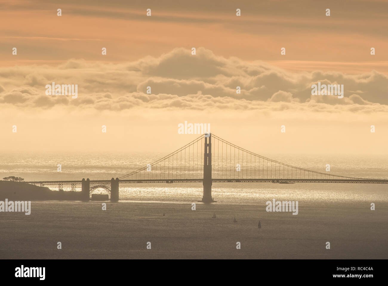 Il Golden Gate Bridge di San Francisco come si vede da lontano in Berkeley Hills durante un bel tramonto quando il cielo era di colore arancione. Foto Stock