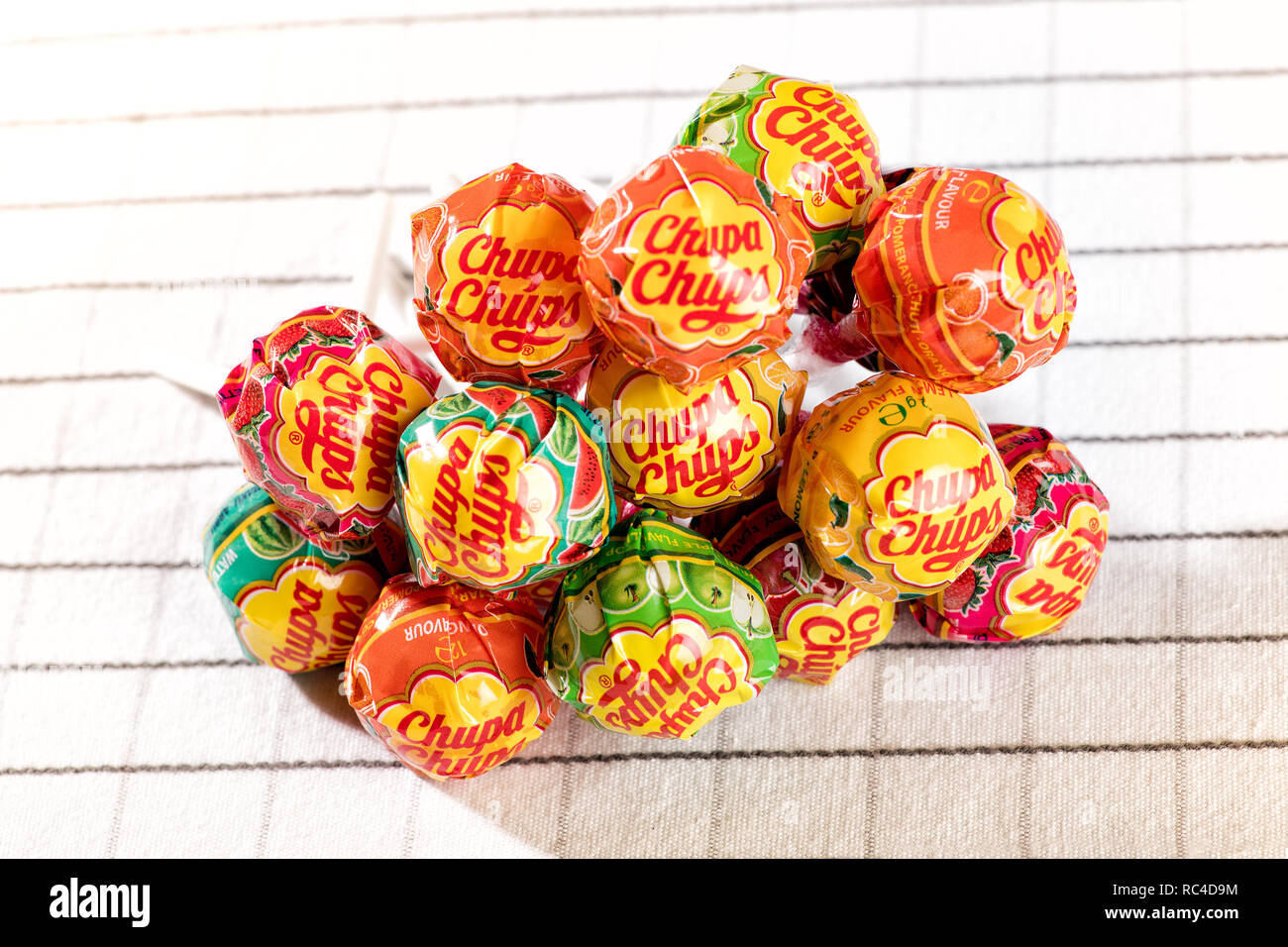 Pila di Chupa Chups lollipop caramelle visto in close-up sul tessuto bianco tovaglia, dall alto angolo Foto Stock