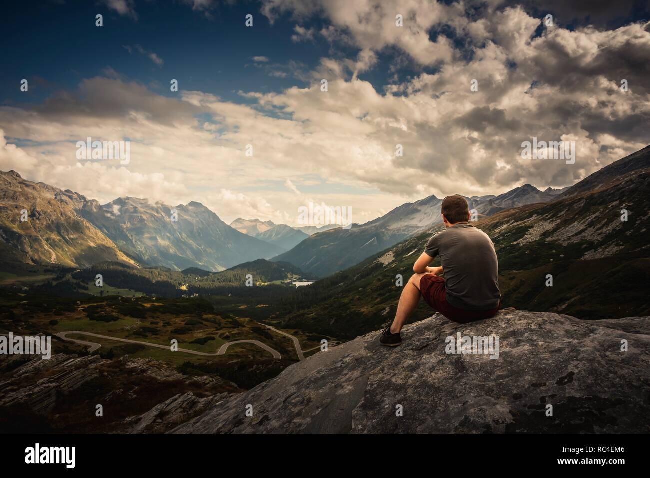 Uomo seduto ammirando la vista di San Bernardino pass, Svizzera Foto Stock