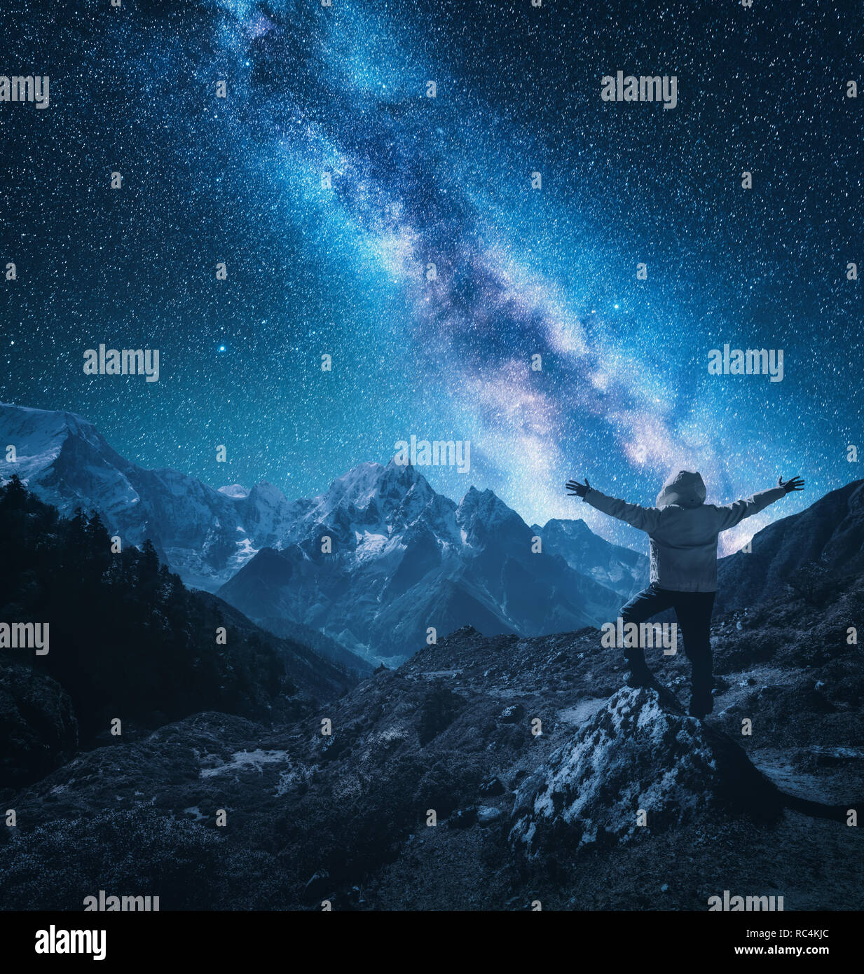Silhouette di un uomo in piedi con sollevata bracci sulla pietra, montagne e il cielo stellato con via lattea di notte in Nepal. Stelle luminose. Viaggio. landsc Foto Stock