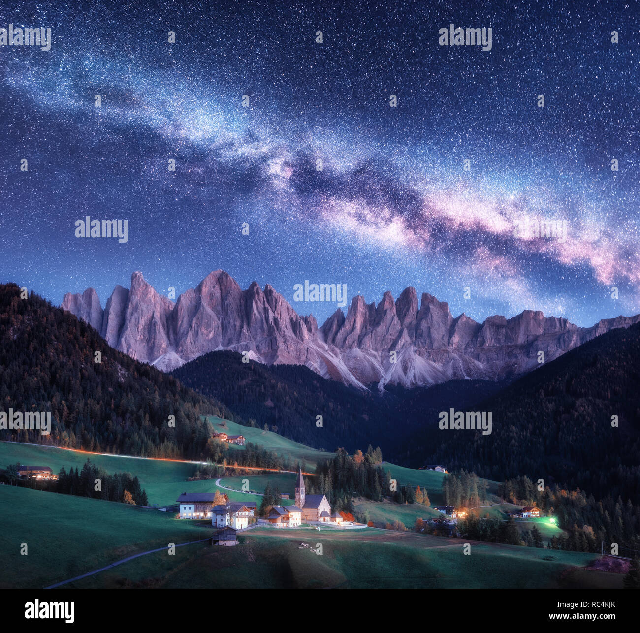 Santa Maddalena e via lattea di notte in autunno in Italia. Cielo stellato con via lattea oltre a Santa Maddalena e le montagne. Villaggio con case, chiesa, gr Foto Stock