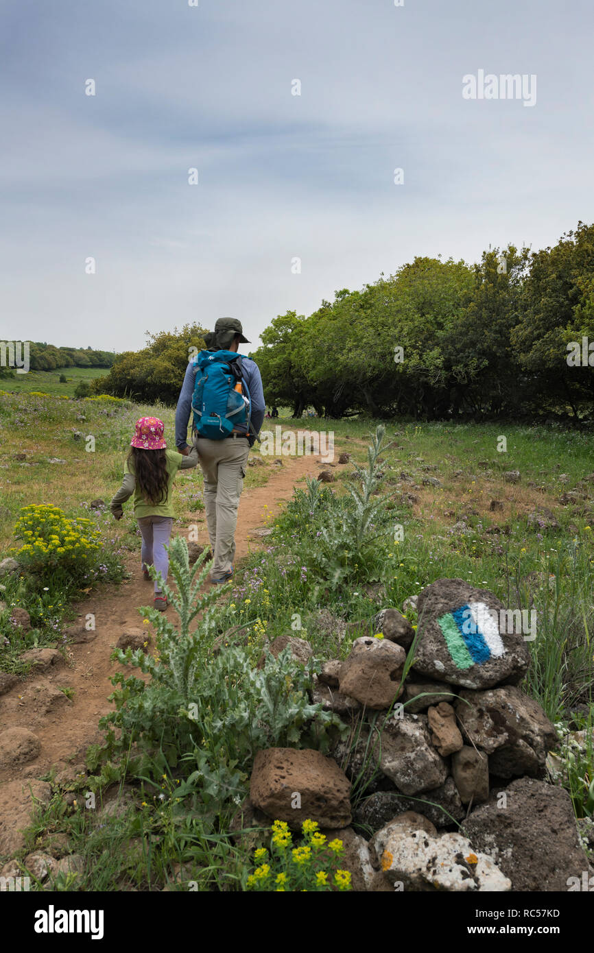 Un padre israeliano che camminava con sua figlia a Golan Heights. Il logo del famoso 'Golan Trail' può essere visto in primo piano. Foto Stock