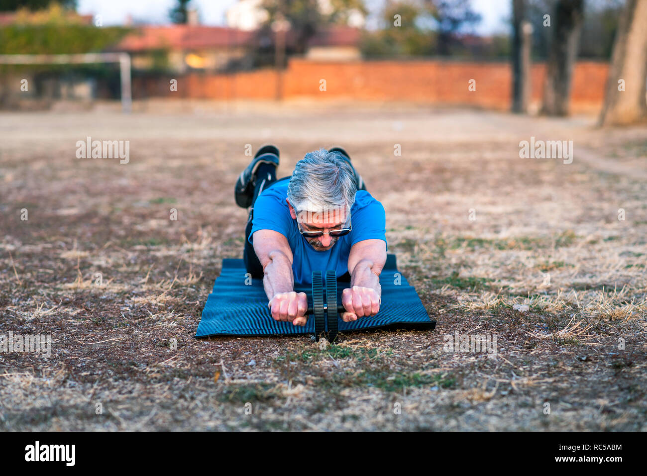 Senior uomo facendo esercizio di abs con un rullo Foto Stock