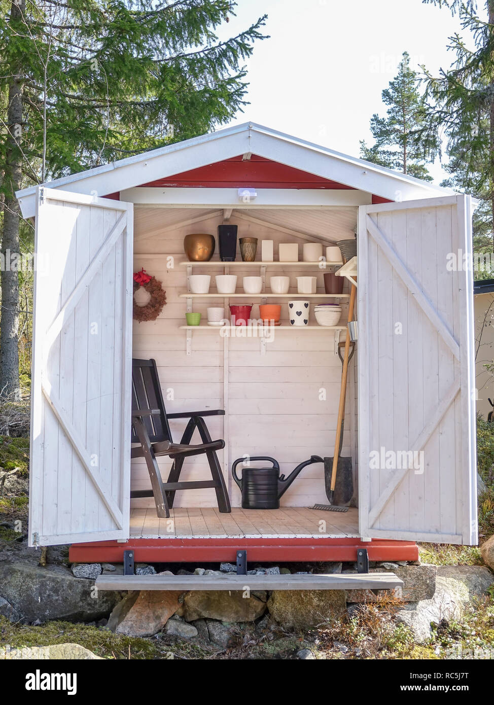 Capannone per il rimessaggio riempito con gli attrezzi da giardino. Badili, rastrello, pentole, brocca e tutto il necessario per il giardinaggio. Foto Stock