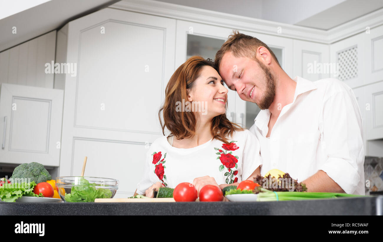 Sorridenti giovani caucasici giovane uomo e donna la cottura di verdure fresche in cucina Foto Stock