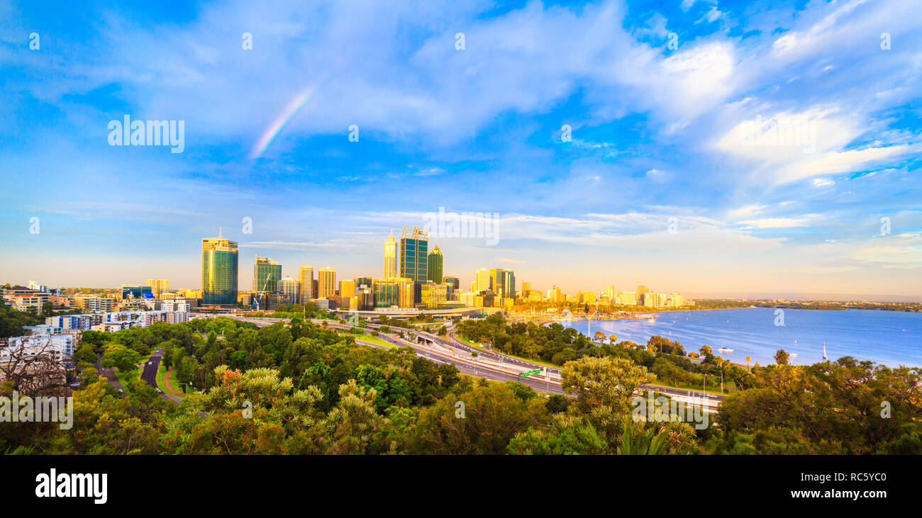 Perth Australia. La città incandescente nel sole del tardo pomeriggio con un overhead di rainbow come vista dal Belvedere in Kings Park, Perth, Western Australia Foto Stock