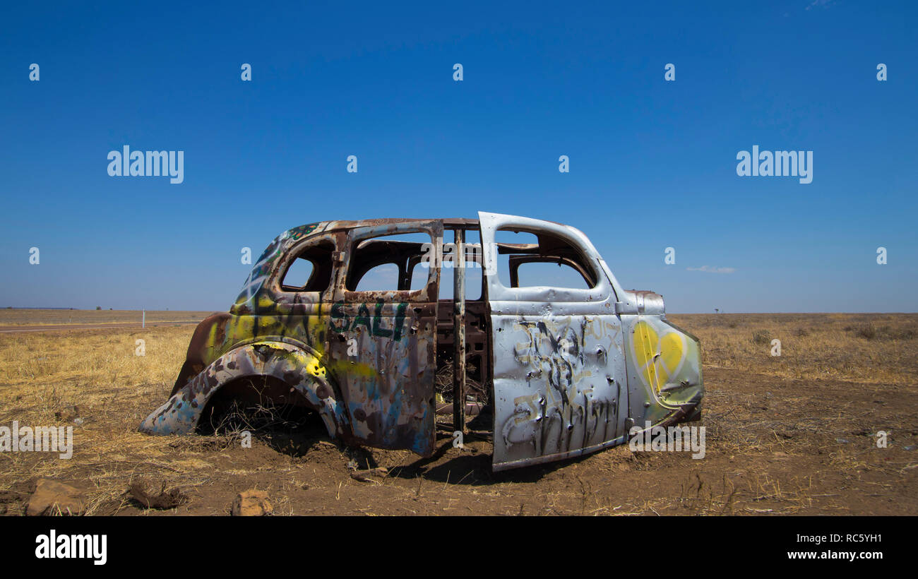 Resti di un vecchio 1940s era autovettura sul lato di una strada in outback Australia con il blu del cielo e spazio di copia Foto Stock