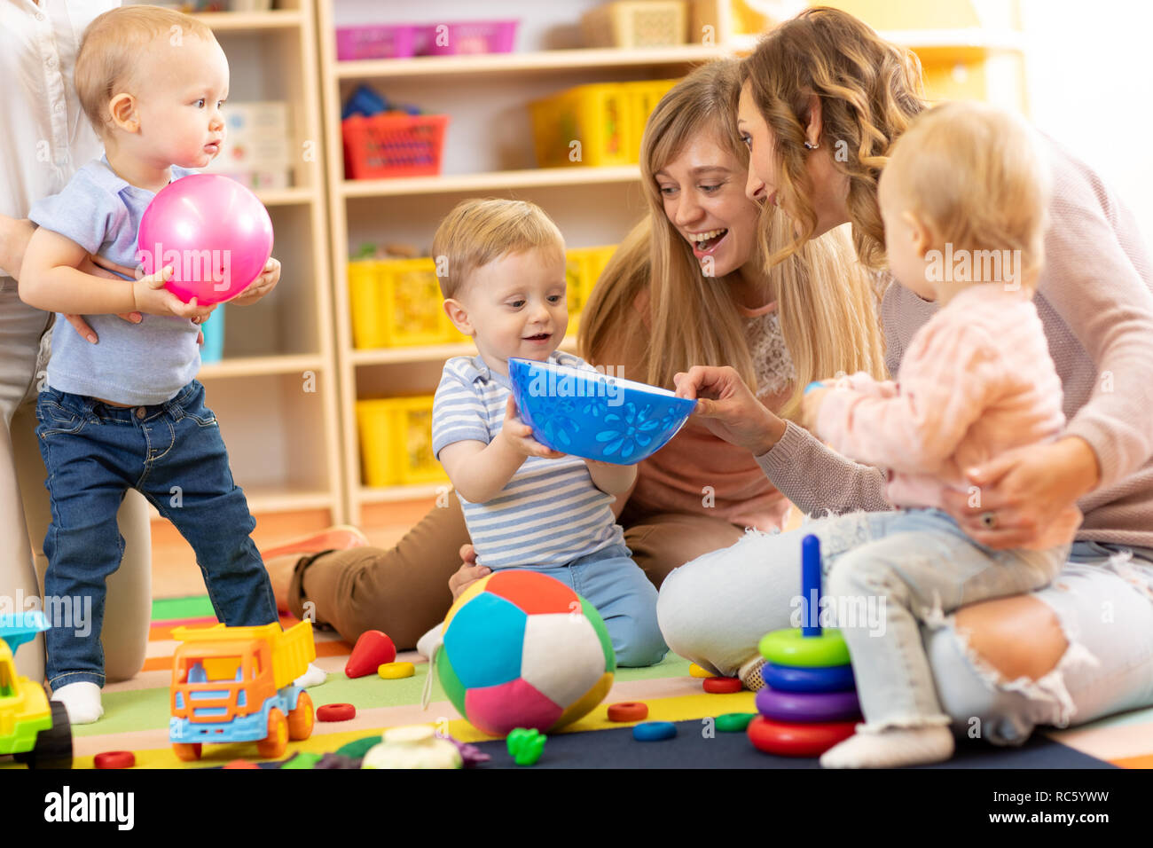 Gruppo di felice mamme con i loro bambini in vivaio Foto Stock