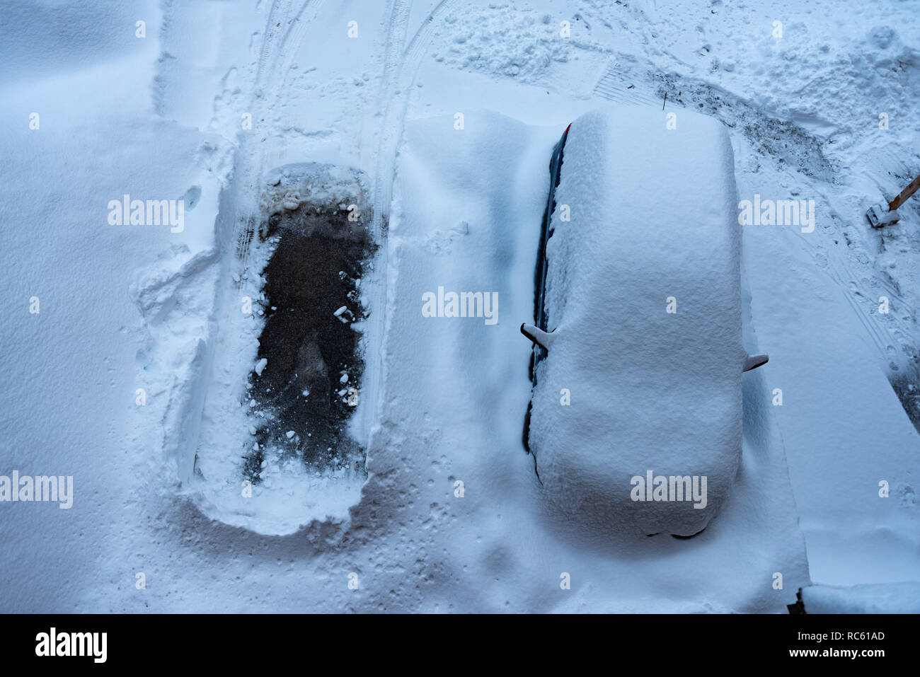 Una macchina parcheggiata sotto un sacco di neve e svuotare lo spazio di parcheggio Foto Stock